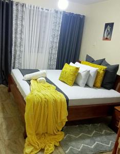 uma cama com almofadas amarelas e um cobertor amarelo em Moh Cabins em Nyeri