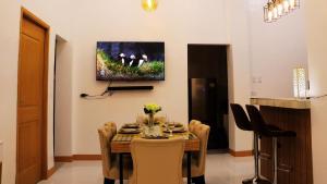 uma mesa de jantar com cadeiras e uma televisão na parede em Caza Lozada em Salaban