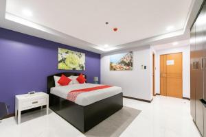 a bedroom with a bed and a purple wall at AMORE HOTEL MANILA in Manila