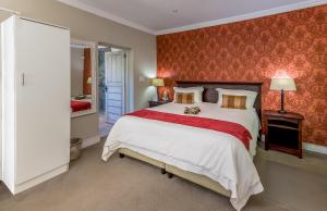 ein Schlafzimmer mit einem großen Bett mit einer roten Wand in der Unterkunft The Rose Cottage B&B in Dullstroom