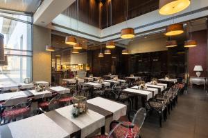 un restaurant avec des tables blanches, des chaises et des lumières dans l'établissement Golden Tulip Ana Dome Hotel, à Cluj-Napoca