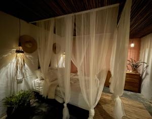 1 cama con cortinas blancas en un dormitorio en Cabaña Aguadulce, en San Rafael
