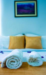 a bed with two rolled towels on a table at The Cascade Munnar in Anachal