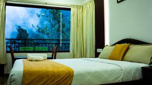 a bedroom with a bed and a large window at The Cascade Munnar in Anachal