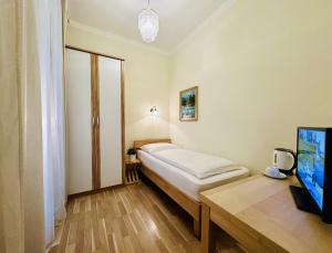 a bedroom with a bed and a desk with a tv at Pension Liechtenstein in Vienna