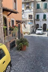 un coche amarillo estacionado en una calle adoquinada con edificios en La Piazzetta, en Tívoli