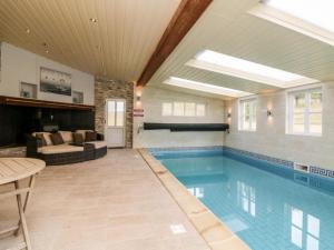 een zwembad in een kamer met een bank en een tafel bij Oak Tree Cottage With Indoor Pool In Devon in Broadwoodkelly