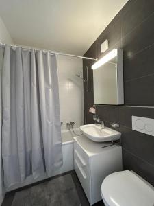 bagno con servizi igienici bianchi e lavandino di Cityscape Prilly près de Lausanne a Prilly
