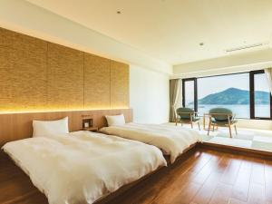 Etajimaにあるえたじま温泉 江田島荘のベッド2台、テーブル、椅子が備わる客室です。