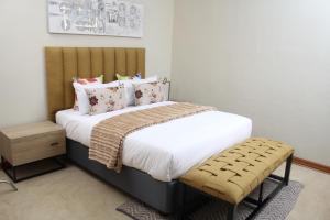 a bedroom with a bed with white sheets and pillows at The Oak Tree House in Gaborone
