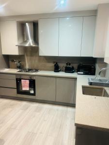 a kitchen with white cabinets and a wooden floor at Icare Lodge Ltd,Safwaan House. in Barking