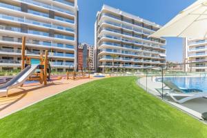 een zwembad met een speeltuin en appartementsgebouwen bij The Style en Pau-5 playa San Juan de Alicante in Alicante