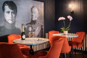 a restaurant with two tables and a painting of a man at Mercure Versailles Paris Ouest in Le Chesnay