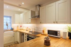 cocina con armarios blancos y encimera de madera en Hythe Townhouse Retreat en Kent