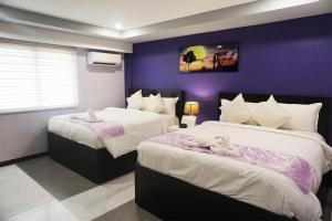 two beds in a room with a purple wall at AMORE HOTEL MANILA in Manila