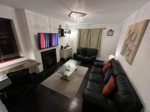 a living room with a black leather couch and a fireplace at Specious 2 x double bedroom flat in London E18 in London