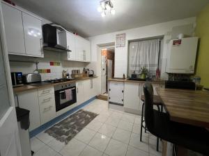 a kitchen with white cabinets and a wooden table at Specious 2 x double bedroom flat in London E18 in London