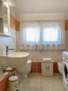ein Bad mit einem Waschbecken, einem WC und einem Fenster in der Unterkunft Il Castelluccio in San Vincenzo