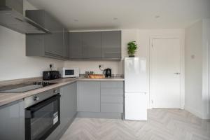 uma cozinha com armários brancos e um frigorífico branco em Woodham House By Horizon Stays em Stockton-on-Tees