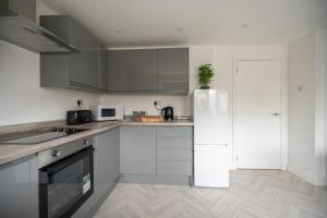 a kitchen with white cabinets and a white refrigerator at Woodham House By Horizon Stays in Stockton-on-Tees