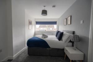 a bedroom with a bed with a blue blanket and a window at Woodham House By Horizon Stays in Stockton-on-Tees