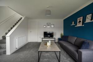 a living room with a couch and a tv at Woodham House By Horizon Stays in Stockton-on-Tees