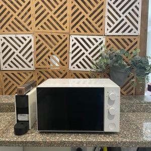 Un four micro-ondes est installé sur un comptoir devant un mur en bois. dans l'établissement Beautiful chalet in Il Monte Galala المونت جلالة ch15-01-01, à Ain Sokhna