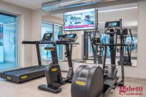 un gimnasio con máquinas cardiovasculares y TV de pantalla plana en Stilicone 15 - Luxury apt 4D, en Milán