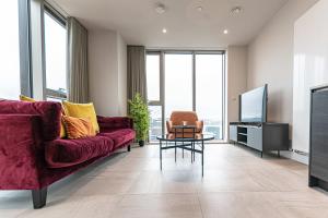 a living room with a red couch and a tv at The Lexington - Luxury Serviced Apartments City Centre - City and Waterfront views in Liverpool