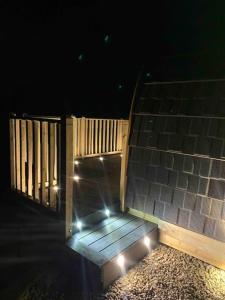 una rampa de madera con luces encendidas por la noche en The Pod Over By en Kilmichael Glassary