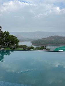 a large swimming pool with a view of a lake at Nisarga Lake Resort in Satara