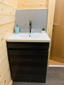 baño con lavabo blanco y armario negro en The Pod Over By en Kilmichael Glassary