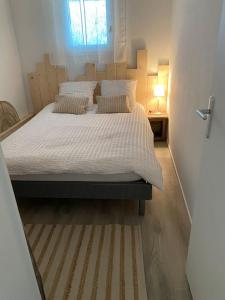 um quarto com uma cama grande com lençóis brancos e almofadas em Les Baigneuses Pontaillac T2 jardin piscine em Vaux-sur-Mer