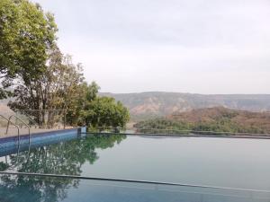 a swimming pool with a view of the mountains at Nisarga Lake Resort in Satara