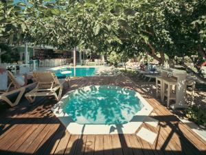 einen Pool mit Stühlen, einem Tisch und einem Baum in der Unterkunft Georgia's Garden by Omilos Hotels in Ammoudara