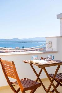 een tafel en stoelen op een balkon met een boek bij Le Tre Caravelle in SantʼAntìoco