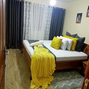 a bedroom with a bed with a yellow blanket on it at Forest Cabins in Nyeri