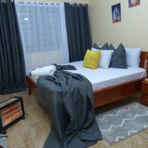 1 dormitorio con cama con sábanas y almohadas negras en Forest Cabins en Nyeri