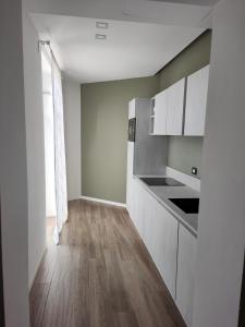 una cucina con armadietti bianchi e pavimenti in legno di CALLA, CALLUNA & GARDENIA APARTMENTS a Verona