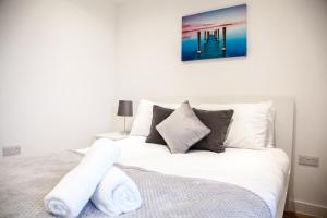 um quarto com uma cama branca e toalhas em Luxury 2 Bed Apartment em Manchester