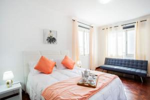 um quarto com uma cama com almofadas laranja e um sofá em Dream Paradise em Água de Pena