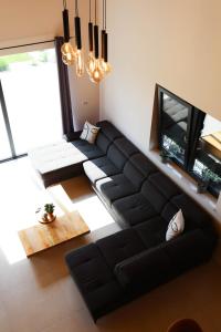 ein Wohnzimmer mit einem schwarzen Sofa und einem TV in der Unterkunft Vikendica Krcmarice- Banja Luka in Banja Luka
