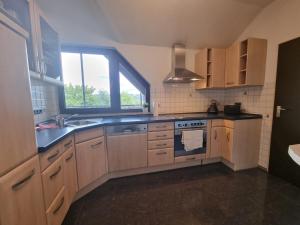 a kitchen with wooden cabinets and a sink and a window at Andinas FeWo - Wunderschöner Ausblick auf den See in Olpe