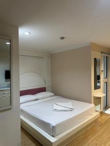 um quarto com uma cama branca com uma toalha em Royal Garden Home Hotel em Banguecoque