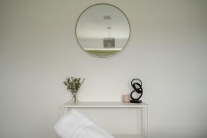 een spiegel op een witte muur boven een witte plank bij Wallington House By Horizon Stays in Stockton-on-Tees