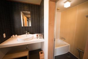 a bathroom with a sink and a mirror and a tub at Ito Kowakien in Ito