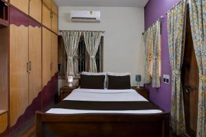 um quarto com uma cama com paredes e cortinas roxas em OYO Brothers Inn em kolkata