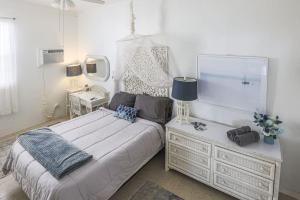 ein weißes Schlafzimmer mit einem Bett und einem Nachttisch in der Unterkunft Annes Revenge The Bonney Overlook in Christiansted