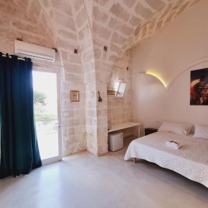 a bedroom with a bed and a large window at Corte Mercurio B&B in Ugento