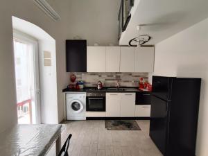 a kitchen with white cabinets and a black refrigerator at La balconata sul mare in Giovinazzo